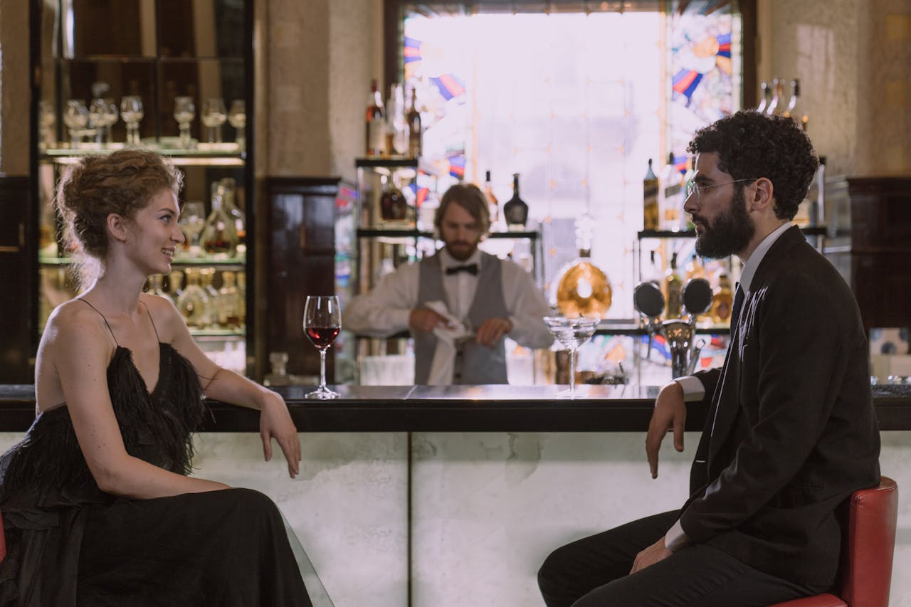 A sophisticated couple enjoys drinks and conversation at a luxurious bar.