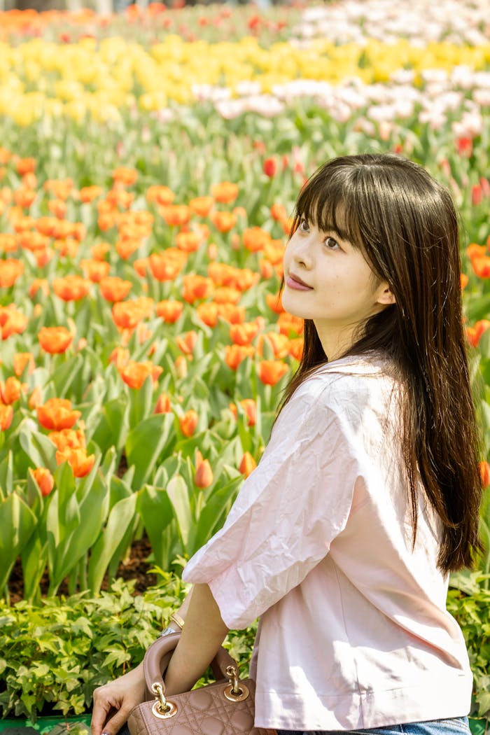 Young woman posing in a vibrant tulip field on a sunny day, creating a cheerful scene.